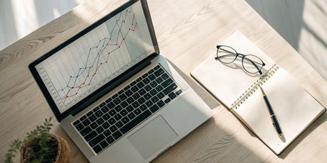 Laptop on a desk with graphs analyzing the advantages and disadvantages of dual pricing.