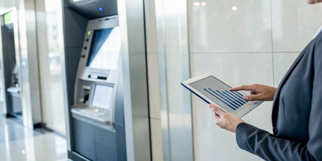 Businessperson evaluating an ATM business for sale by analyzing data on a tablet.